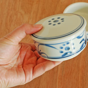 砥部焼・梅山窯　太陽柄の二段ふた物（小）を手に持って