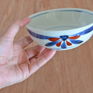 砥部焼・梅山窯　ごす赤菊の多用鉢（4.7寸）を手に持って