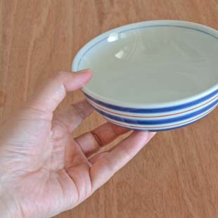 砥部焼・梅山窯　あい赤ラインの多用鉢（4.7寸）を手に持って