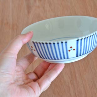 砥部焼・梅山窯　とくさみつ紋の多用鉢（4.7寸）を手に持って