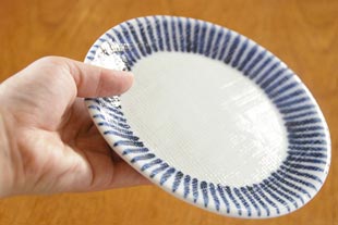 砥部焼・梅山窯　とくさ柄の布目丸皿を手に持って