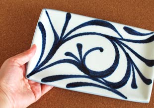 砥部焼・梅山窯　からくさの布目角皿(7.5寸)を手に持って