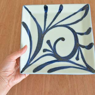 砥部焼・梅山窯　からくさの布目正角皿(7寸)を手に持って