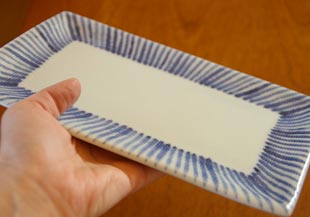 砥部焼・梅山窯　とくさ柄の布目角皿(7寸)を手に持って