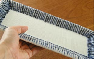 砥部焼・梅山窯　とくさ柄の布目角皿(9寸)を手に持ったところ