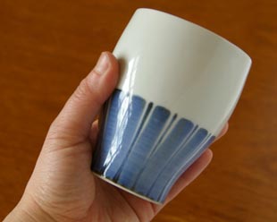 砥部焼・梅山窯　たてしま柄のフリーカップを手に持って