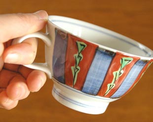 砥部焼・梅山窯　色絵模様のコーヒーカップを手に持って