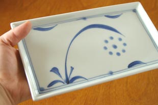 砥部焼・梅山窯　太陽柄の角皿を手に持って