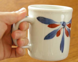 砥部焼・梅山窯　花もようのマグカップを手に持って