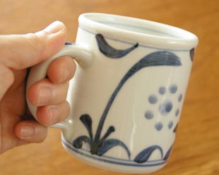 砥部焼・梅山窯　太陽柄のマグカップを手に持って