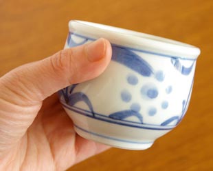 砥部焼・梅山窯　太陽柄の玉ぶち湯呑を手に持って