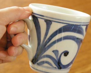 砥部焼・梅山窯　からくさのモーニングカップを手に持って