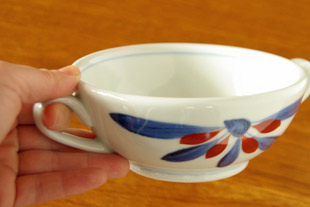 砥部焼・梅山窯　ごす赤菊のスープカップ＆ソーサーを持って