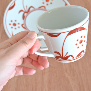 砥部焼・梅山窯　赤太陽のコーヒーカップを手に持って