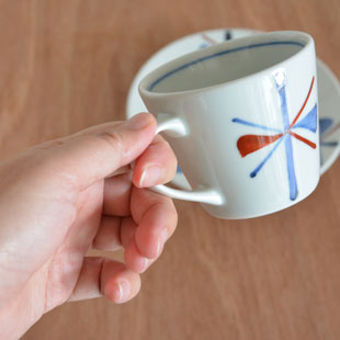 砥部焼・梅山窯　赤蝶文のコーヒーカップを手に持って
