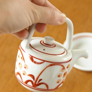 砥部焼・梅山窯　赤太陽の醤油さしを手に持って