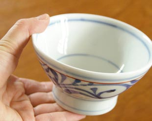 砥部焼・梅山窯　赤線からくさの茶碗(小)を手に持って