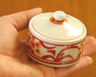 砥部焼・梅山窯　赤太陽の薬味入れを手に持って