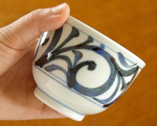 砥部焼・梅山窯 からくさの湯呑を手に持って