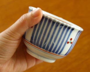 砥部焼・梅山窯　とくさみつ紋の湯呑を手に持って