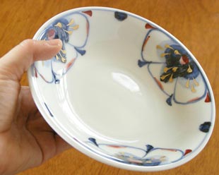 砥部焼・西岡工房　蝶花柄の深皿を手に持って