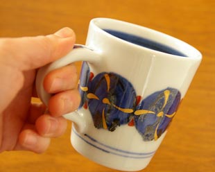 砥部焼・西岡工房　ごすまる柄のマグカップを手に持って