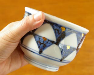 砥部焼・西岡工房　ゴスペン柄の湯呑を手に持って