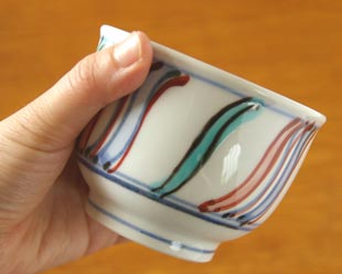 砥部焼・西岡工房　よろけもようの湯呑を手に持って