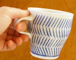 砥部焼・中田窯　はけめ模様のマグカップを手に持って