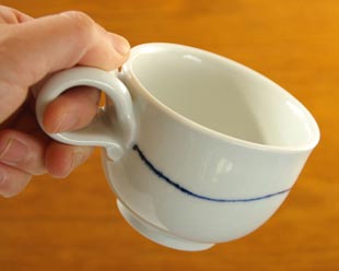 砥部焼・向井窯　白いコーヒーカップを手に持って