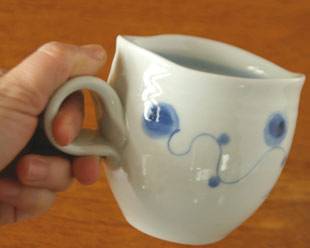砥部焼・向井窯　青玉のくねくねマグを手に持って