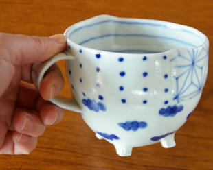 砥部焼・スギウラ工房　はりあわせ足付マグを手に持って