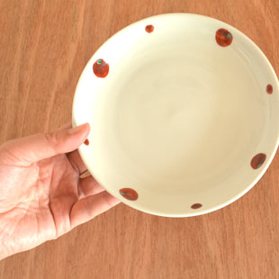 砥部焼・陶房遊　赤玉の取皿(5寸)を手に持って