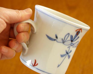 砥部焼・陶房遊　花ちらしのマグカップを手に持って