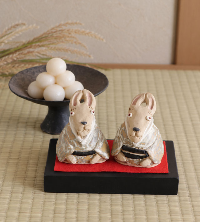 黒い木製飾り台と赤い敷布に並ぶお座りうさぎ